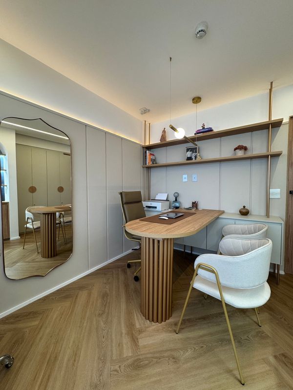 Consultório com mesa de atendimento, cadeiras, estante e espelho