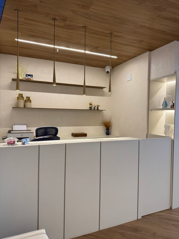 Balcão da recepção, com prateleiras e iluminação pendente